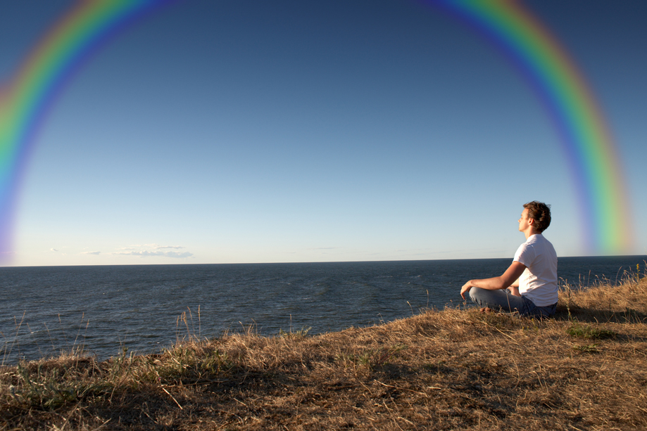 man meditating with a rainbow