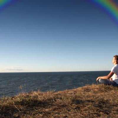 man meditating with a rainbow