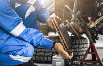 Mechanic Asian man close up fixing repairing car rotor spindle hub automobile vehicle parts examining using tools equipment working hard in workshop garage support and service in overall work uniform